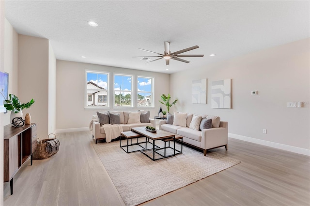 living room featuring a textured ceiling, light hardwood / wood-style flooring, and ceiling fan