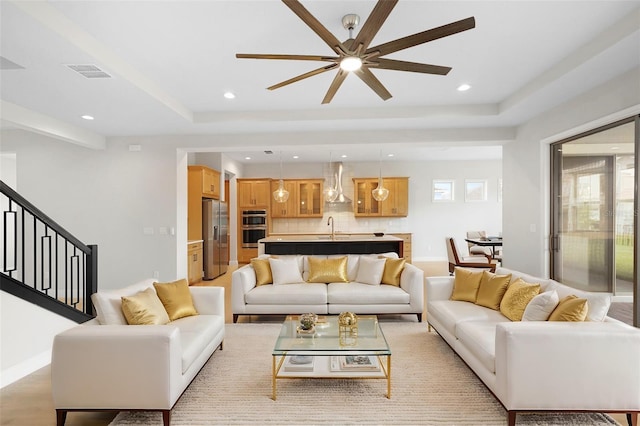 living room featuring light hardwood / wood-style flooring, ceiling fan, and sink