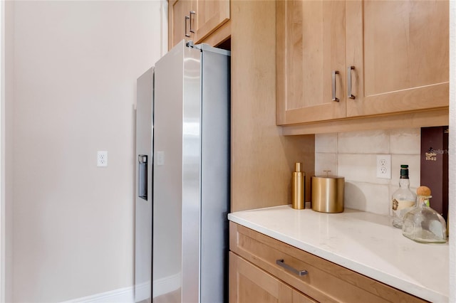 kitchen with stainless steel refrigerator with ice dispenser, tasteful backsplash, and light brown cabinetry