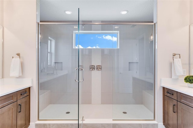 bathroom featuring a shower with shower door and vanity