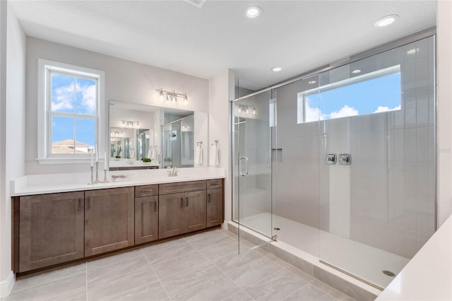 bathroom featuring a shower with door and vanity