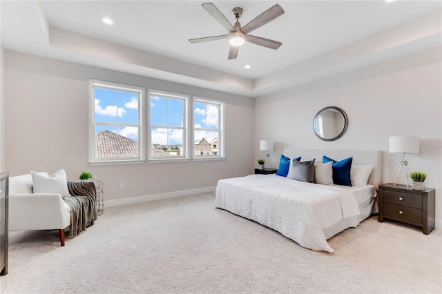 carpeted bedroom featuring a tray ceiling and ceiling fan