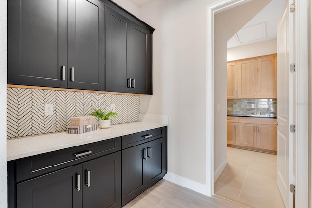 interior space with light brown cabinetry, sink, light tile patterned floors, and backsplash