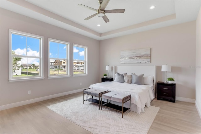 bedroom featuring a tray ceiling, ceiling fan, and light hardwood / wood-style floors