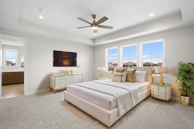 carpeted bedroom with a tray ceiling and ceiling fan