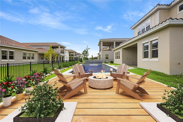 deck featuring a fire pit, pool water feature, and a fenced in pool