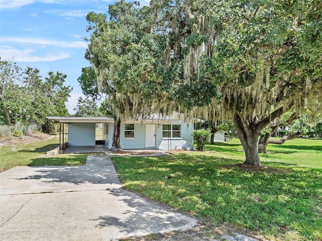 view of front facade with a carport, concrete driveway, and a front lawn