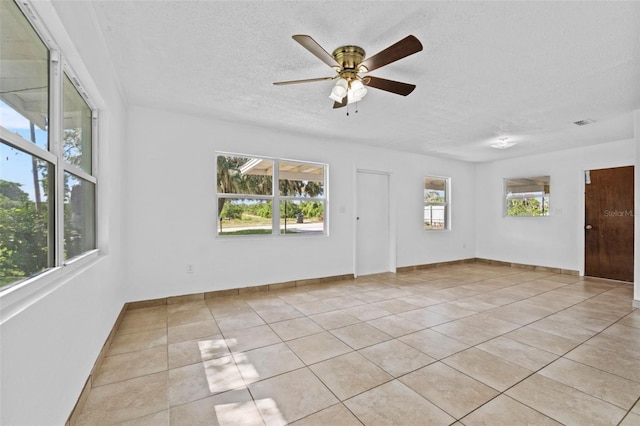 unfurnished room with a healthy amount of sunlight, light tile patterned floors, a ceiling fan, and a textured ceiling