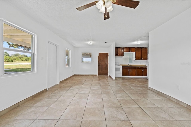 unfurnished living room with ceiling fan, a textured ceiling, and light tile patterned floors