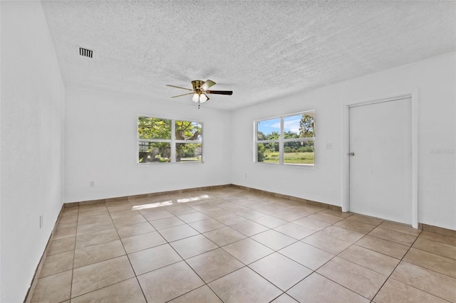 empty room featuring ceiling fan, a textured ceiling, light tile patterned flooring, and visible vents