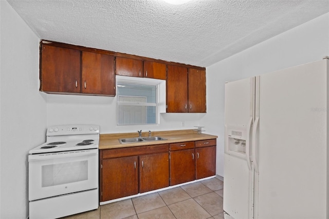 kitchen featuring white appliances, brown cabinets, light countertops, a sink, and light tile patterned flooring