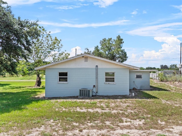 rear view of house featuring a lawn and central air condition unit