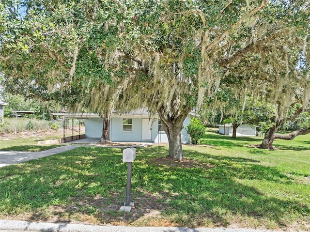 view of front facade featuring driveway, an attached carport, and a front yard