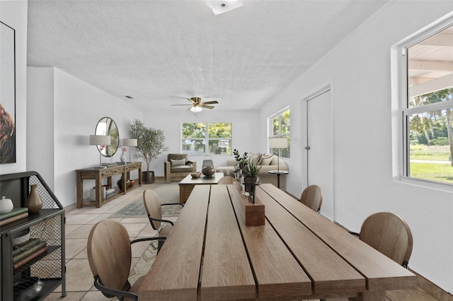 dining area featuring light tile patterned floors, ceiling fan, and a textured ceiling