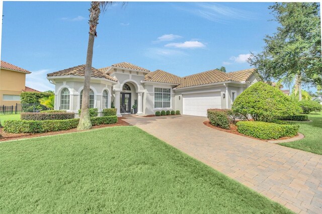 mediterranean / spanish home featuring a garage and a front yard