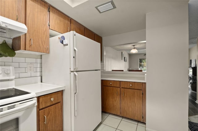 kitchen with light tile patterned floors, white appliances, and decorative backsplash