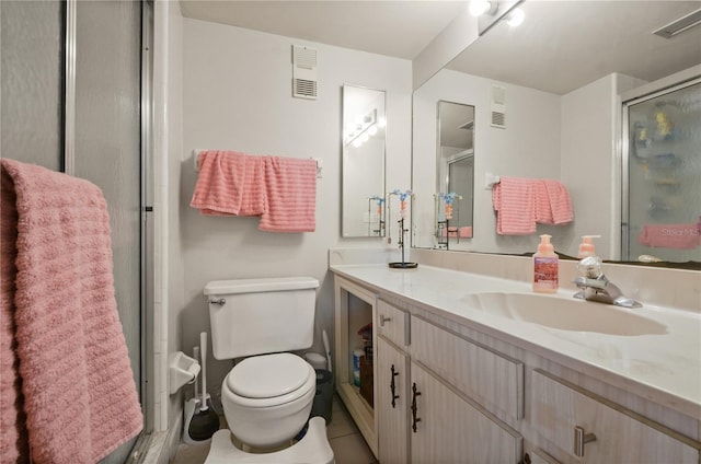 bathroom featuring vanity, toilet, an enclosed shower, and tile patterned floors