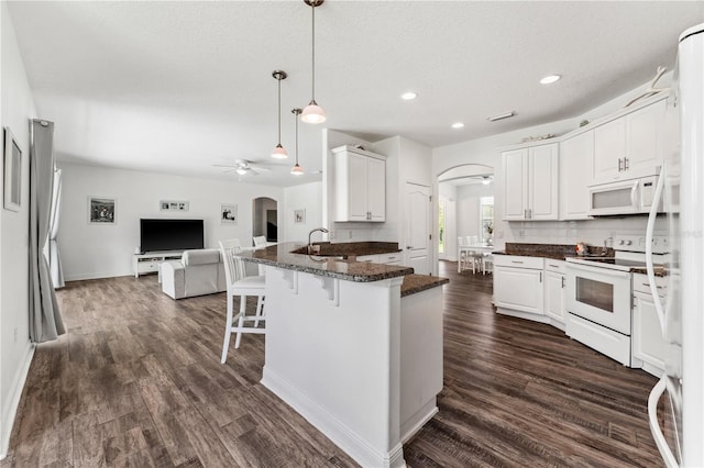 kitchen with white cabinets, white appliances, ceiling fan, dark wood-type flooring, and a kitchen breakfast bar