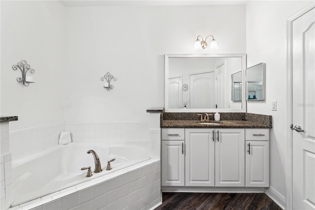 bathroom with vanity, wood-type flooring, and tiled bath