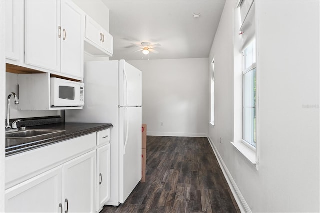 kitchen featuring a healthy amount of sunlight, ceiling fan, white appliances, and dark wood-type flooring