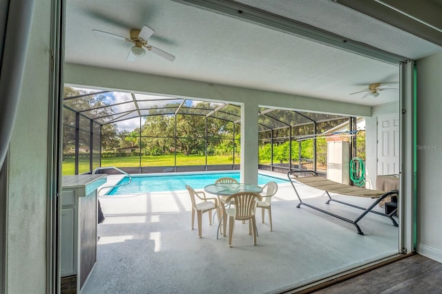 view of pool featuring glass enclosure, ceiling fan, and a patio area