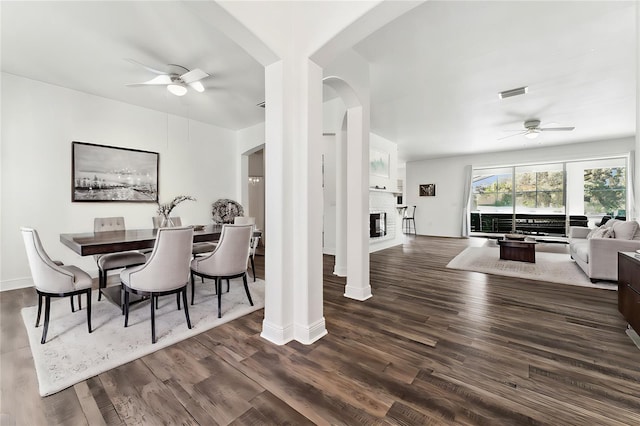 dining space with ceiling fan, a fireplace, and dark hardwood / wood-style floors