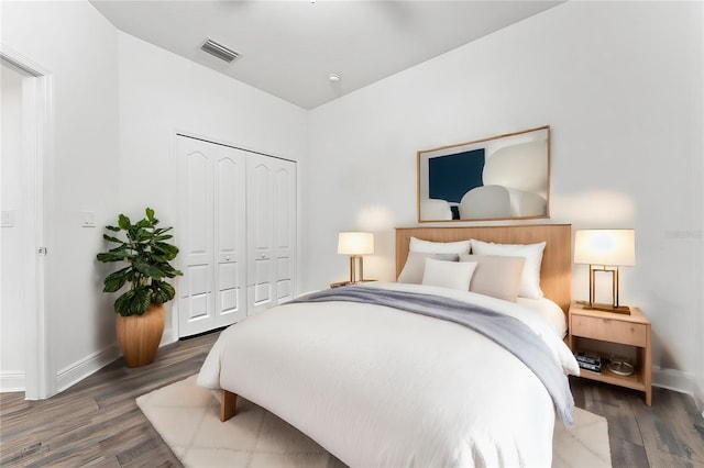 bedroom with dark hardwood / wood-style flooring and a closet