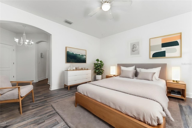 bedroom featuring dark hardwood / wood-style floors and ceiling fan with notable chandelier