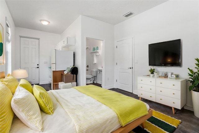 bedroom with dark wood-type flooring and connected bathroom