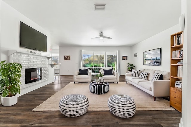 living room with ceiling fan, dark hardwood / wood-style floors, and a brick fireplace