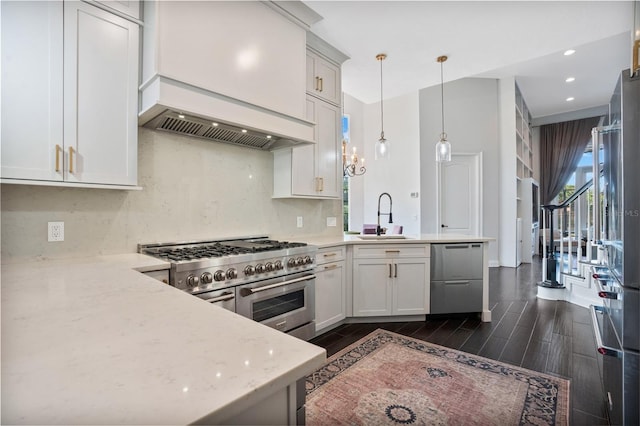 kitchen featuring appliances with stainless steel finishes, hanging light fixtures, dark wood-type flooring, light stone counters, and sink