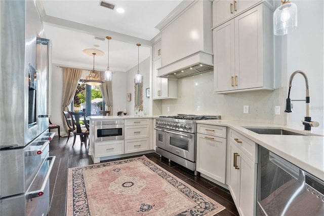 kitchen with pendant lighting, dark wood-type flooring, white cabinetry, stainless steel appliances, and crown molding