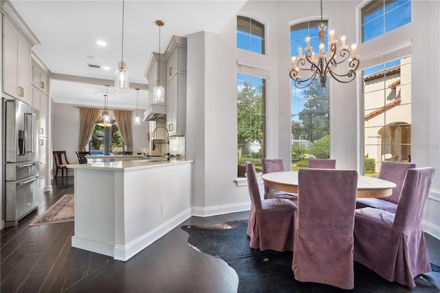 dining area featuring an inviting chandelier, dark hardwood / wood-style floors, sink, and a healthy amount of sunlight