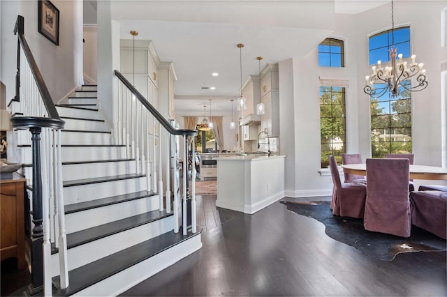 foyer with an inviting chandelier, a high ceiling, sink, and dark hardwood / wood-style flooring