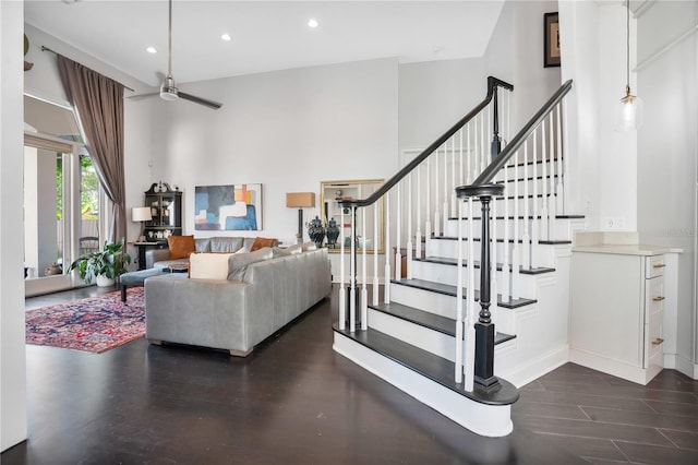 interior space featuring a towering ceiling, ceiling fan, and dark wood-type flooring