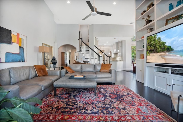 living room featuring a towering ceiling, ceiling fan, and built in features