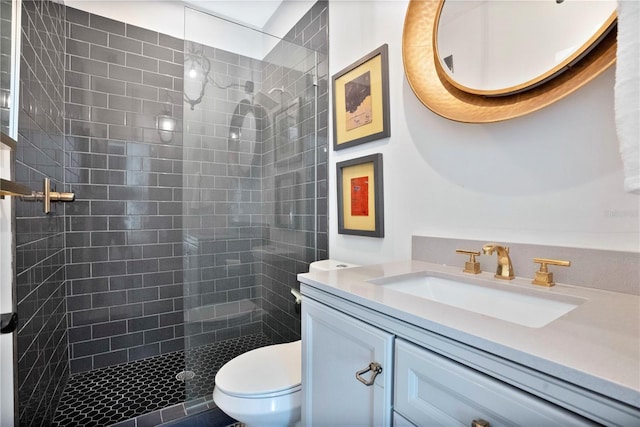 bathroom with tiled shower, vanity, and toilet