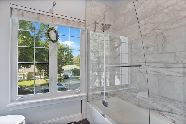 bathroom featuring tiled shower / bath combo, toilet, and a healthy amount of sunlight