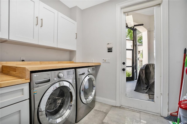 laundry area featuring cabinets, independent washer and dryer, and light tile patterned floors