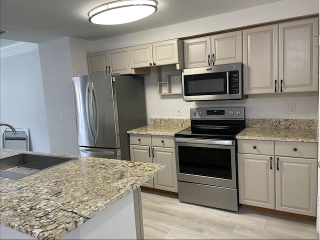 kitchen featuring light stone countertops, appliances with stainless steel finishes, light wood-type flooring, and sink