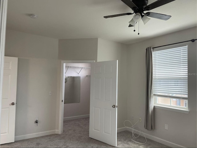 unfurnished bedroom featuring multiple windows, a spacious closet, ceiling fan, and a closet