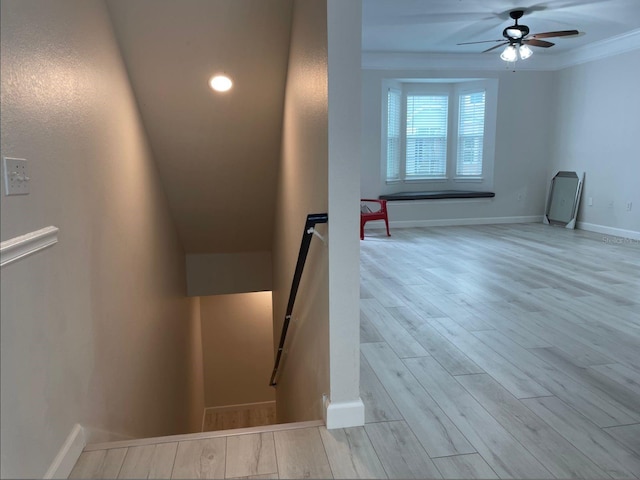 stairs with ceiling fan, crown molding, and hardwood / wood-style floors