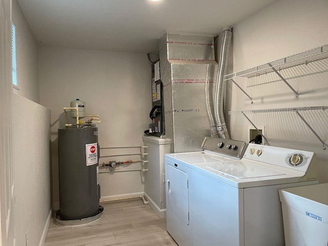 clothes washing area featuring light wood-type flooring, water heater, sink, and washing machine and dryer