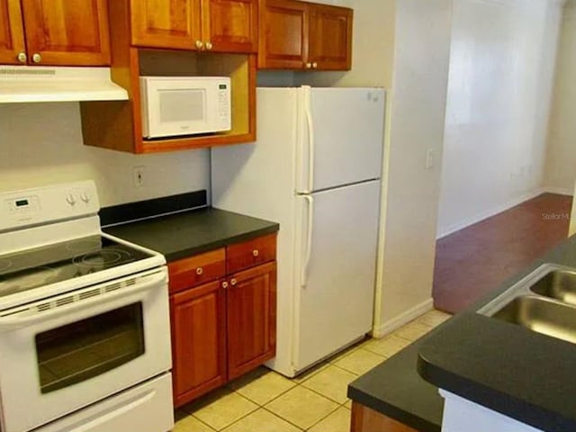 kitchen with white appliances, light tile patterned floors, and sink