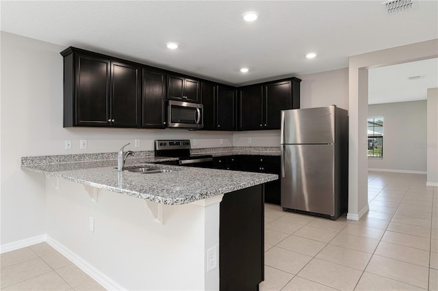 208 Hyacinth Ct, Kissimmee, FL 34759 - kitchen with stainless steel appliances, a peninsula, a sink, light stone counters, and light tile patterned floors