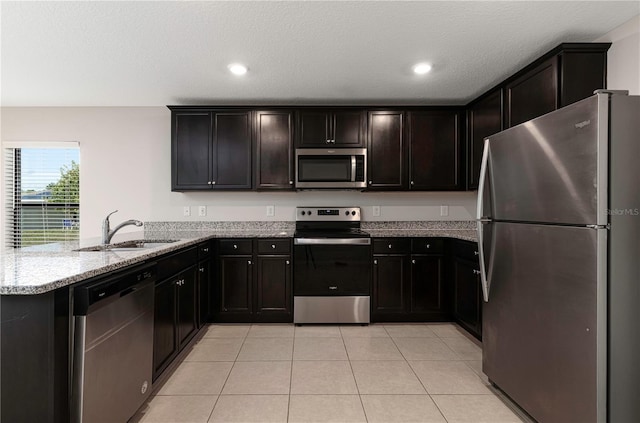 208 Hyacinth Ct, Kissimmee, FL 34759 - kitchen with stainless steel appliances, a sink, light stone countertops, a peninsula, and light tile patterned floors