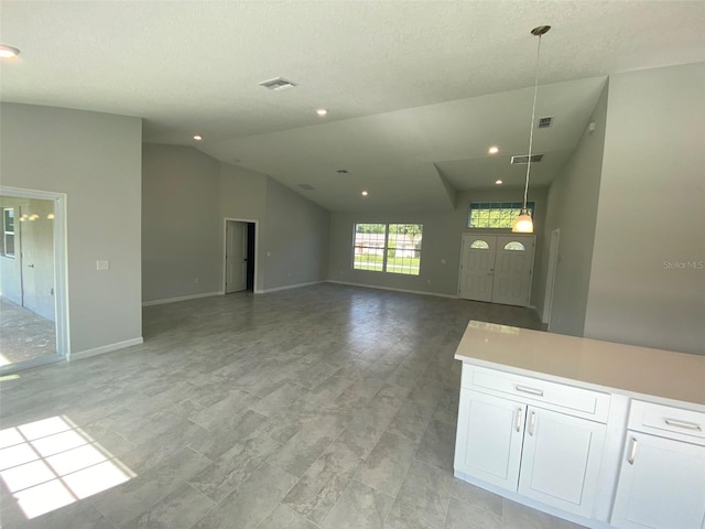 unfurnished living room featuring vaulted ceiling and a textured ceiling