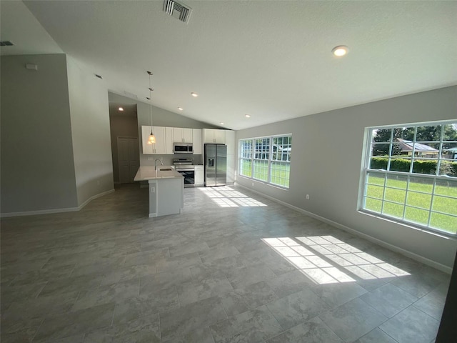 interior space with lofted ceiling, a healthy amount of sunlight, stainless steel appliances, and white cabinetry