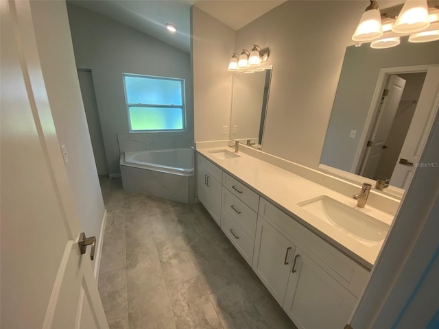 bathroom with lofted ceiling, vanity, tiled tub, and a notable chandelier