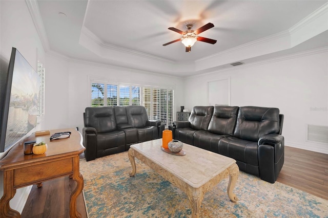 living room featuring crown molding, a raised ceiling, ceiling fan, and wood-type flooring